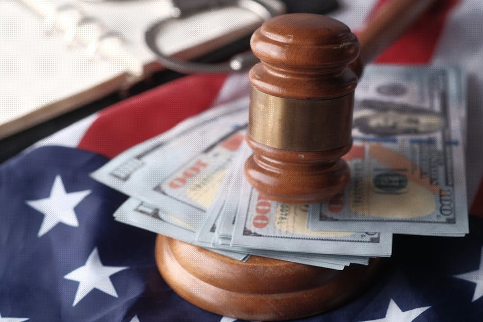 Close-up of a judge's gavel resting on US dollar bills and an American flag, symbolizing justice and finance.